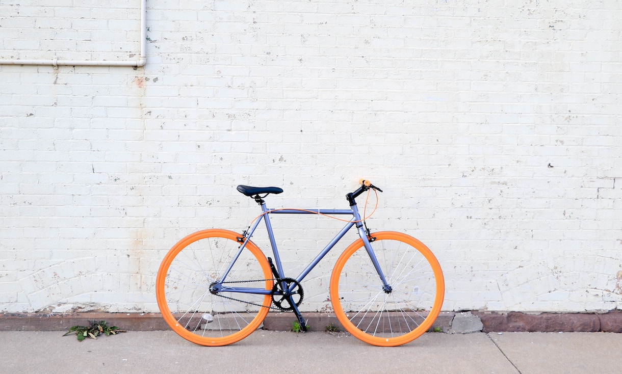 Orange and purple bike leaning against a white brick wall